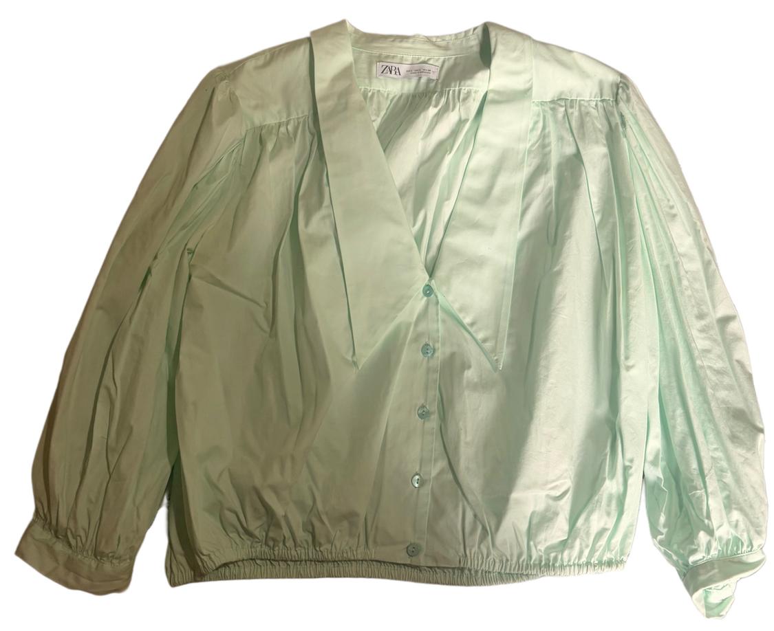 Light green blouse with a V-neck and puff long sleeves. Front buttons and elasticated cuffs and hem. "ZARA" tag.