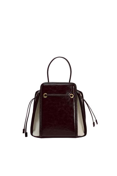Black leather handbag with handles and lace detailing on the sides, on a white background. Elegant and modern design.