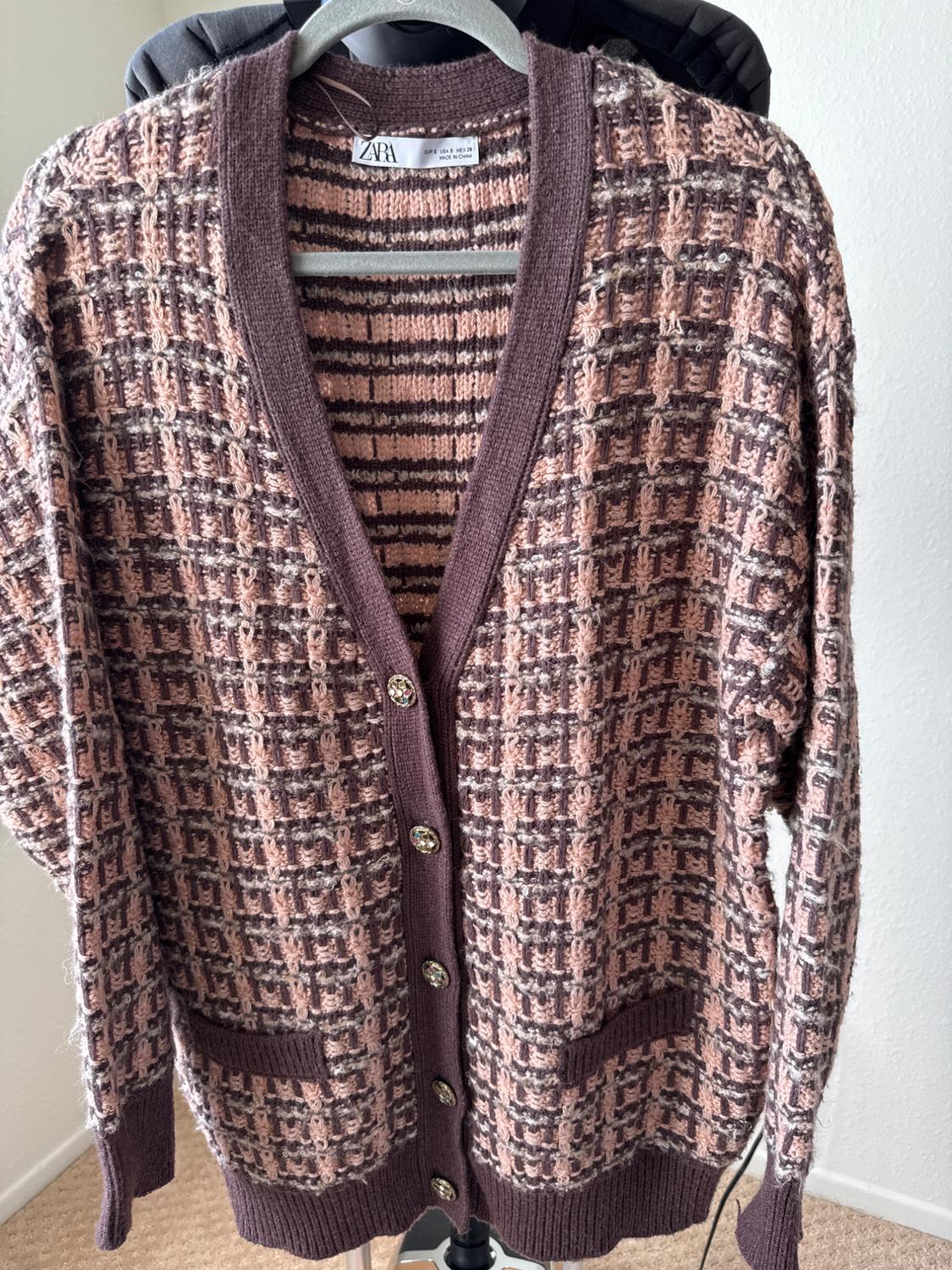 Front view of a textured cardigan with front pockets and decorative buttons.