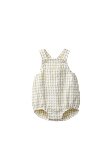 Front view of a light green baby romper with a checked print and front pocket. Buttoned straps and puffed legs.