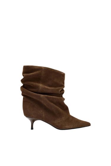 Brown, low-heeled, pointed-toe boot with a crinkled design on the body, on a white background.