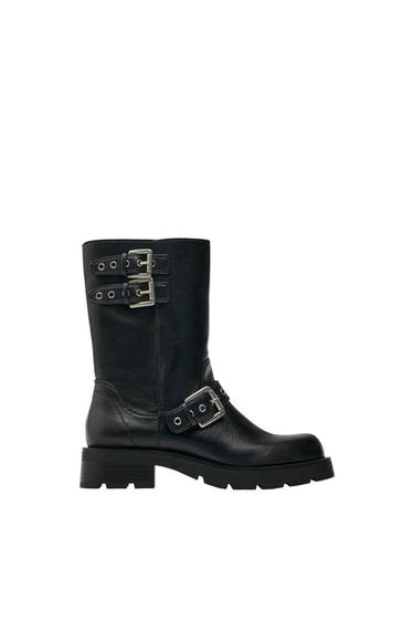 Black mid-calf boot with a chunky lug sole and three silver buckles on a white background.