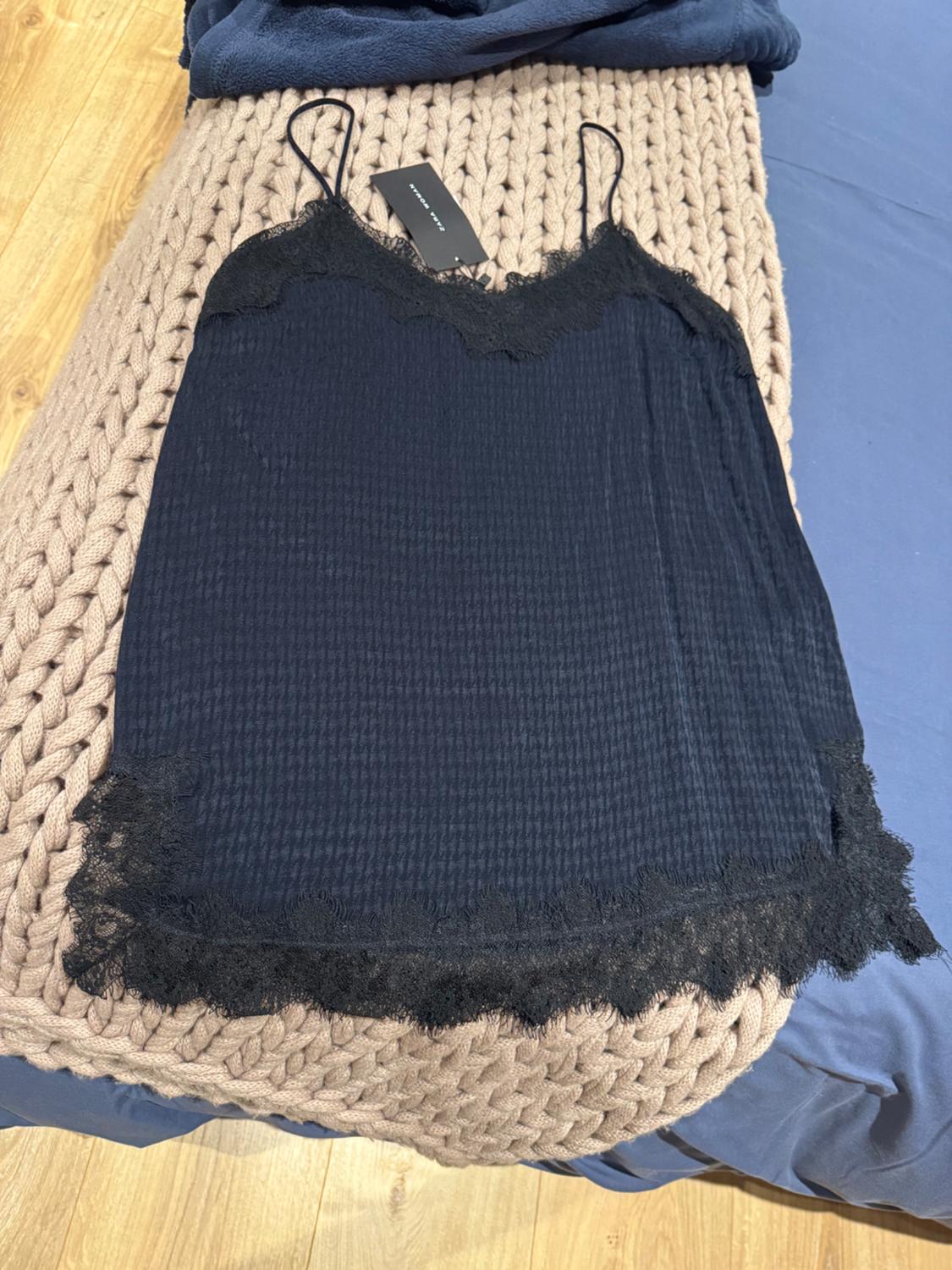 Black nightdress with lace trim, on a beige knitted blanket. Black label visible at the top.
