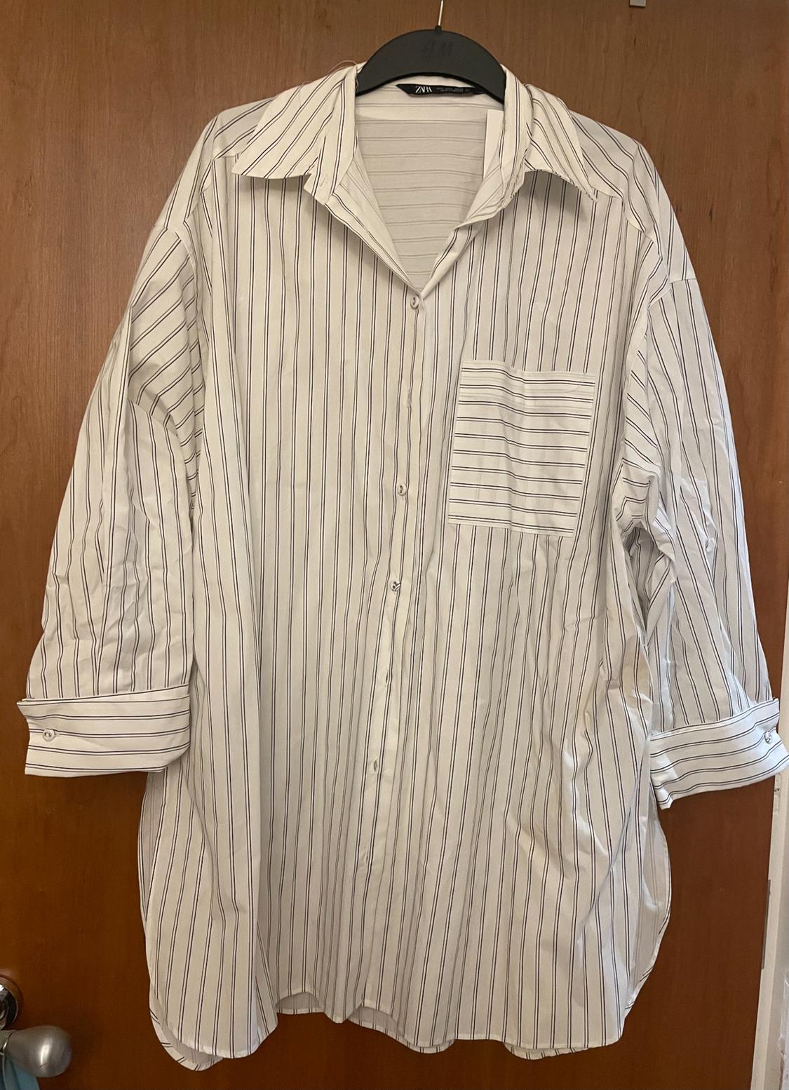 Black and white vertical striped shirt hanging on a black hanger over a wooden door.
