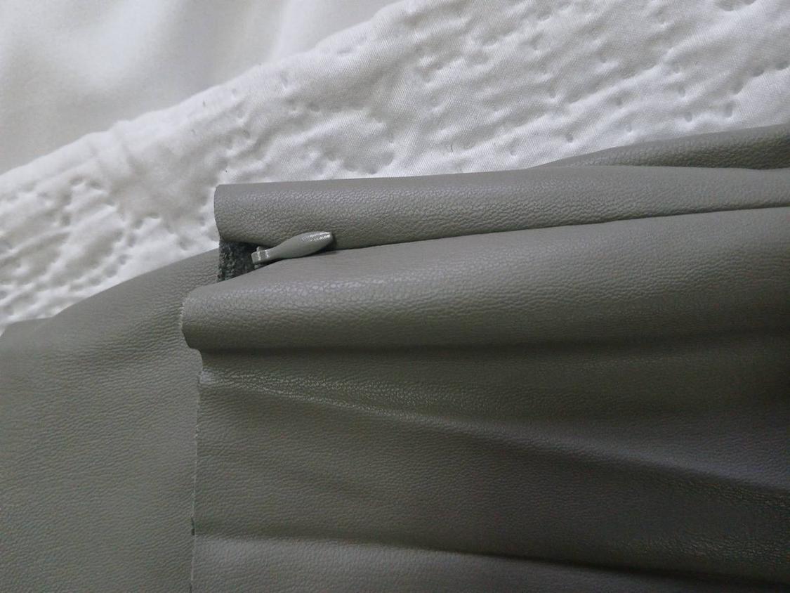 Grey zip closure on textured white fabric. The image shows a detail of the material's texture and colour.