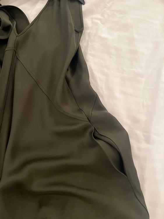 Olive green satin dress on a white surface, showing stitching details and a smooth texture.
