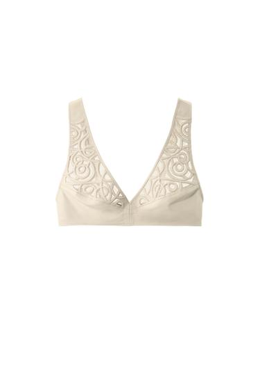 Front view of a beige bra with decorative lace trim at the neckline.