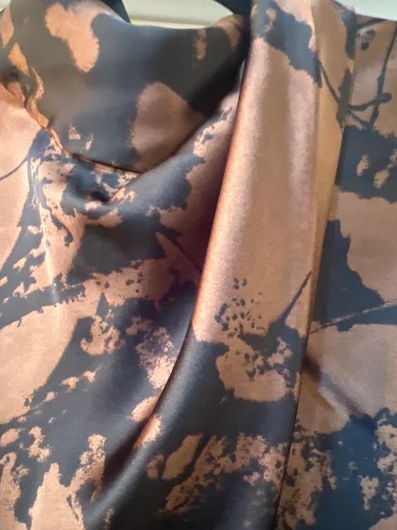 Satin fabric with an abstract print in brown and black tones, with soft pleats that create an elegant and fluid effect.