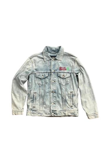 Light blue denim jacket on a white background with a distressed wash, pockets, and the text THIRST FOR ADVENTURE on the chest.