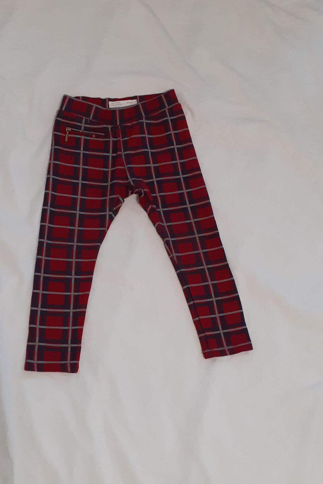 Front view of red and black checked trousers with a front zip pocket.