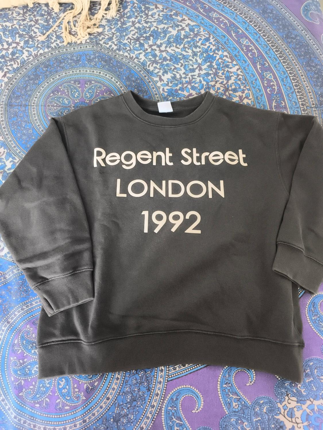 Dark grey sweatshirt with the text “Regent Street LONDON 1992” on a fabric printed in shades of blue and purple.