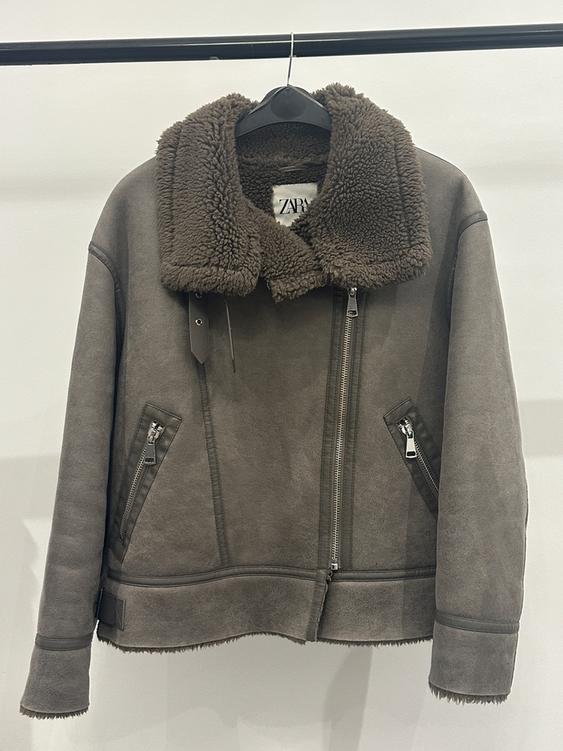 Grey jacket with brown wool collar, front zip fastening and zip pockets, hanging on a black hanger. Visible label: ZARA.
