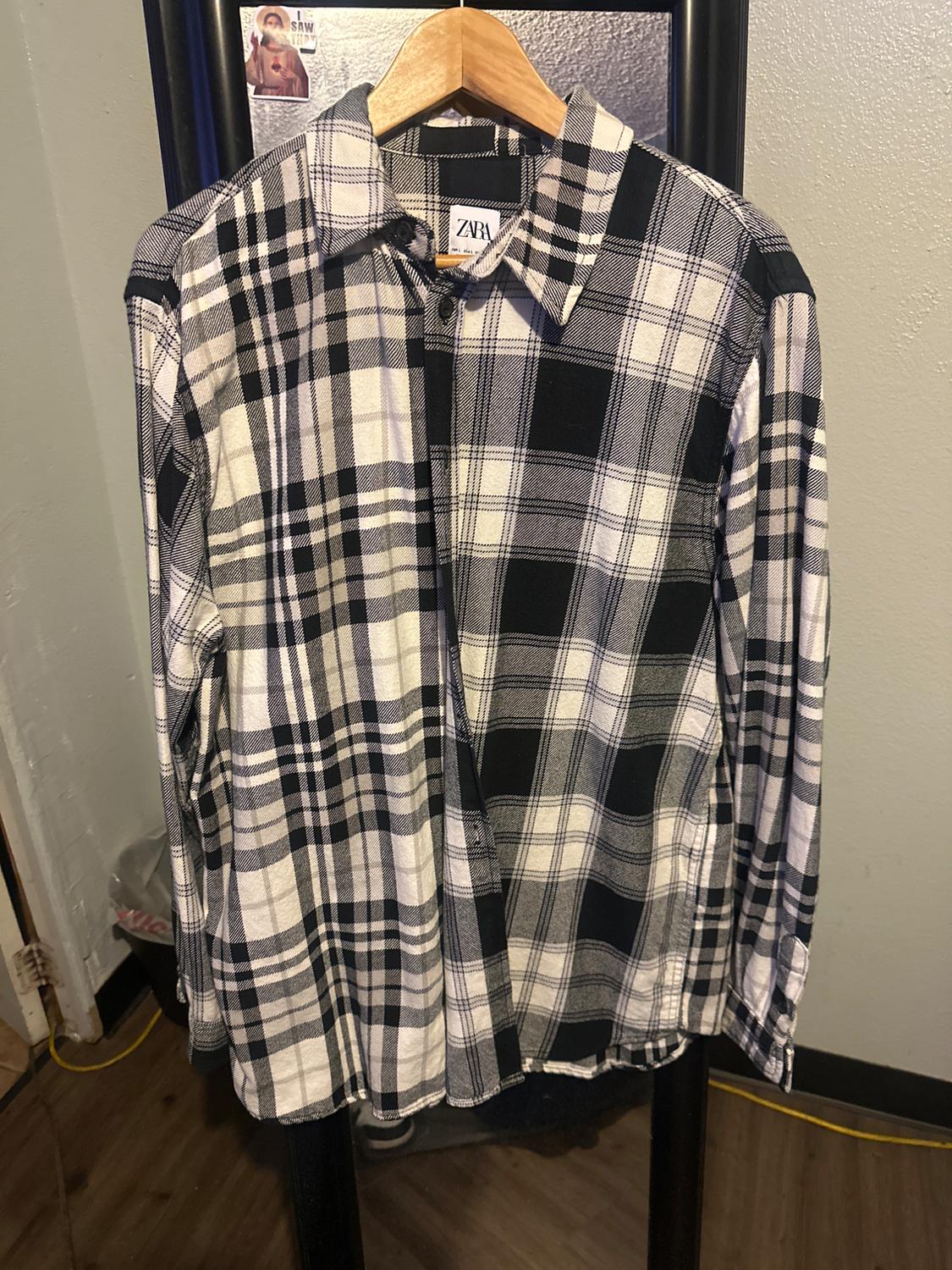 Black and white checked shirt hanging on a wooden hanger. Visible label with the text "ZARA". Grey wall background.