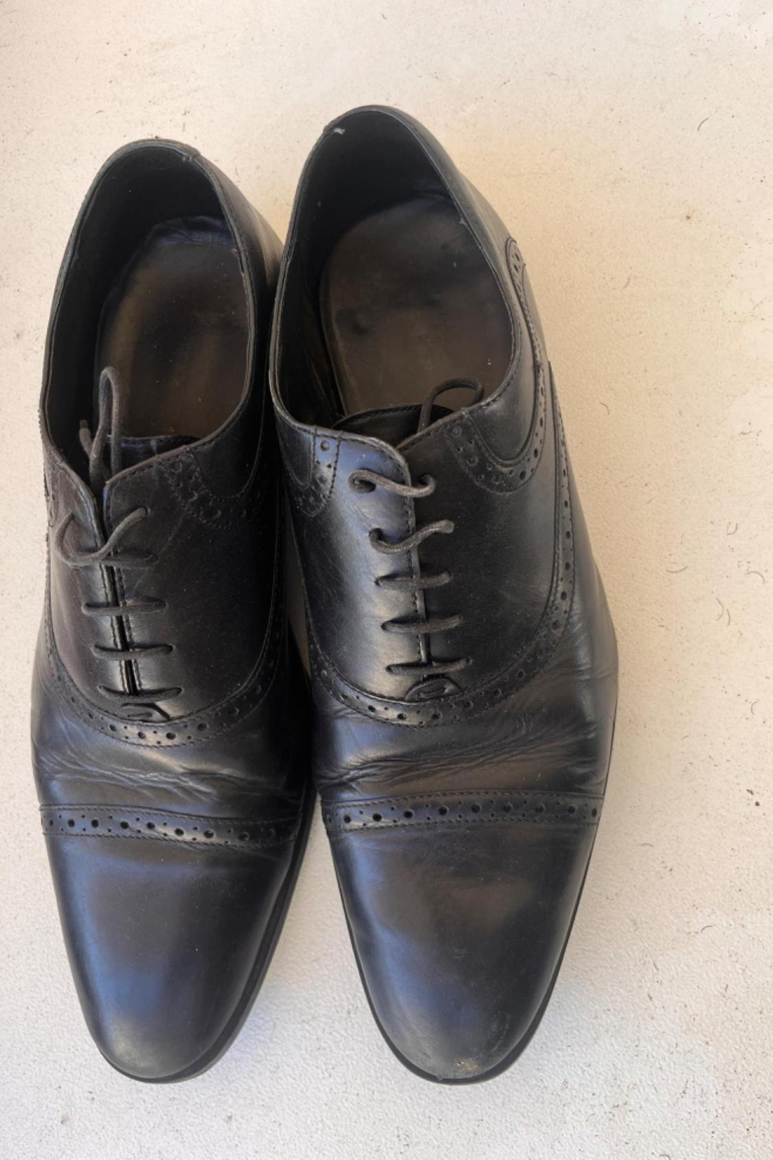 Black Oxford shoes with decorative broguing and visible laces.