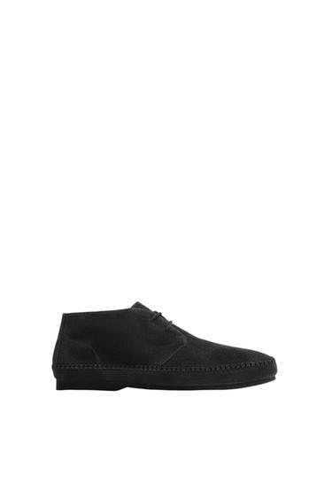 Side view of a grey lace-up ankle boot with visible stitching on the sole.