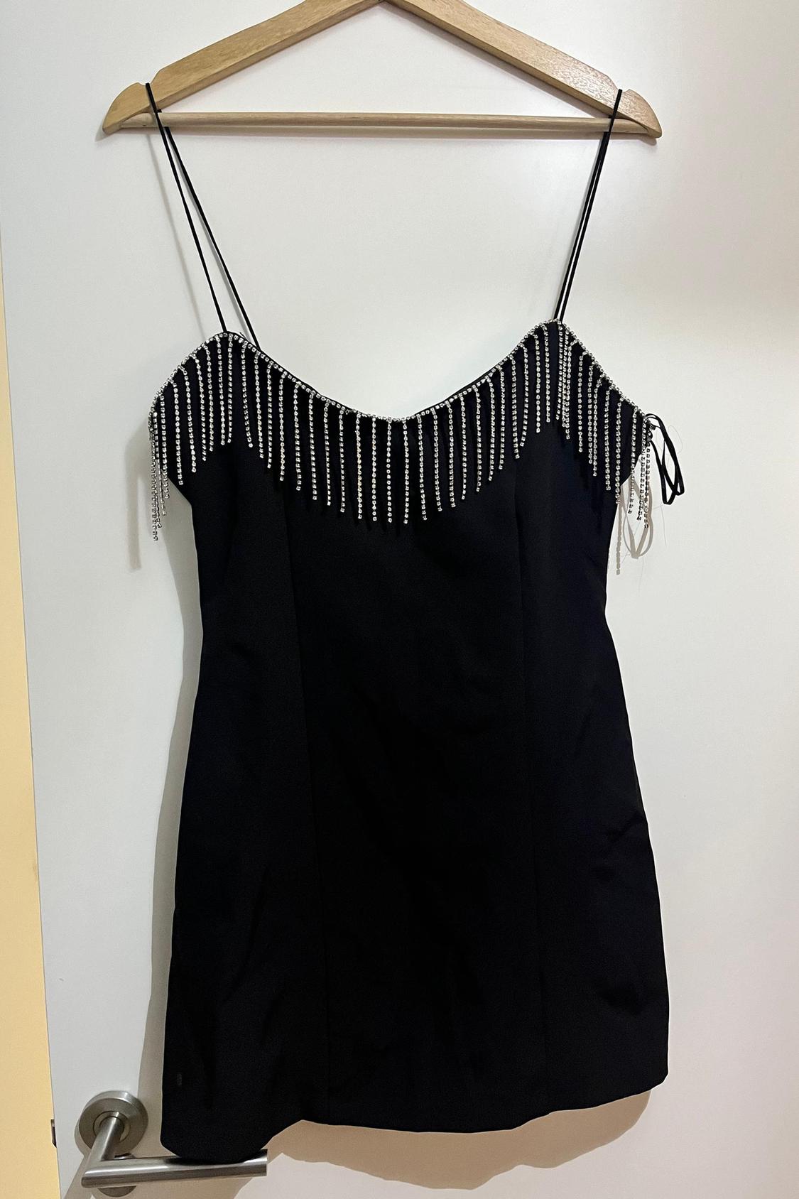 Front view of black dress with thin straps and pearl embellishments on the neckline.