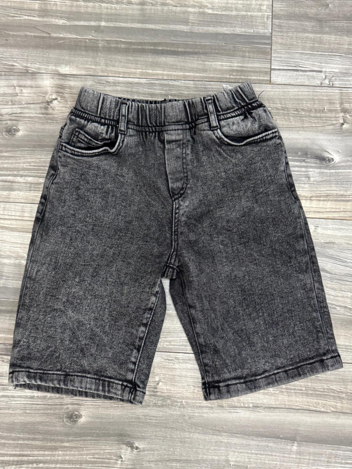 Dark grey denim shorts with a washed effect, an elasticated waist and pockets, against a wooden background.