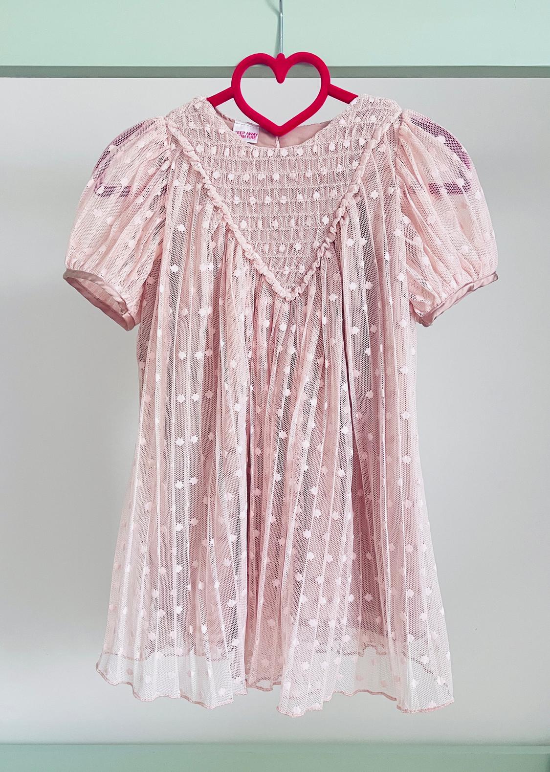 Light pink dress with puff sleeves and lace details, hanging on a red heart-shaped hanger.