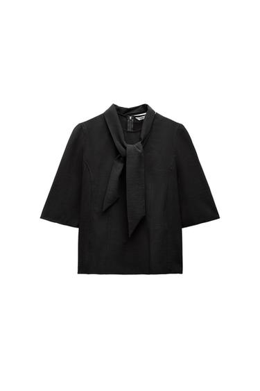 Front view of a black blouse with a necktie and short sleeves.