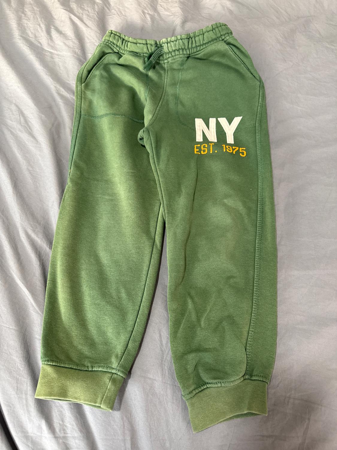 Green sports trousers with elasticated waist and pockets. "NY EST. 1975" text in white and yellow on the left leg.