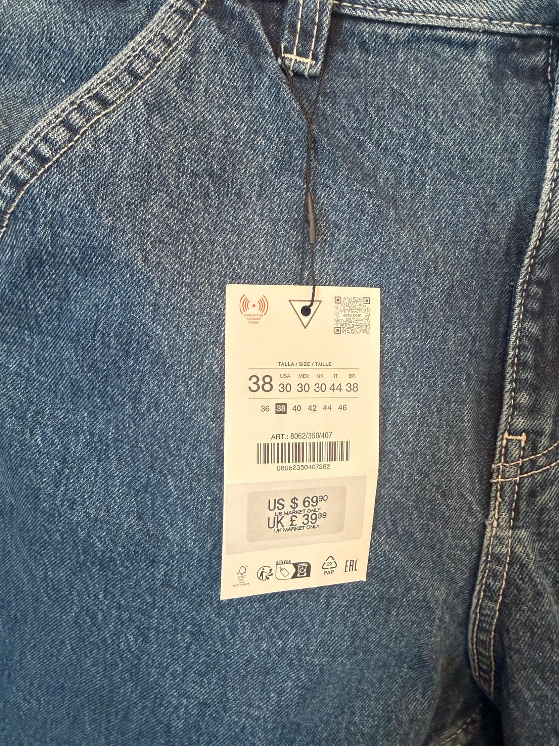 Close-up of blue denim fabric with label. Text: SIZE / SIZE / TAILLE 38 ART.: 8062/350/407 US $ 69.90 UK £ 39.99.