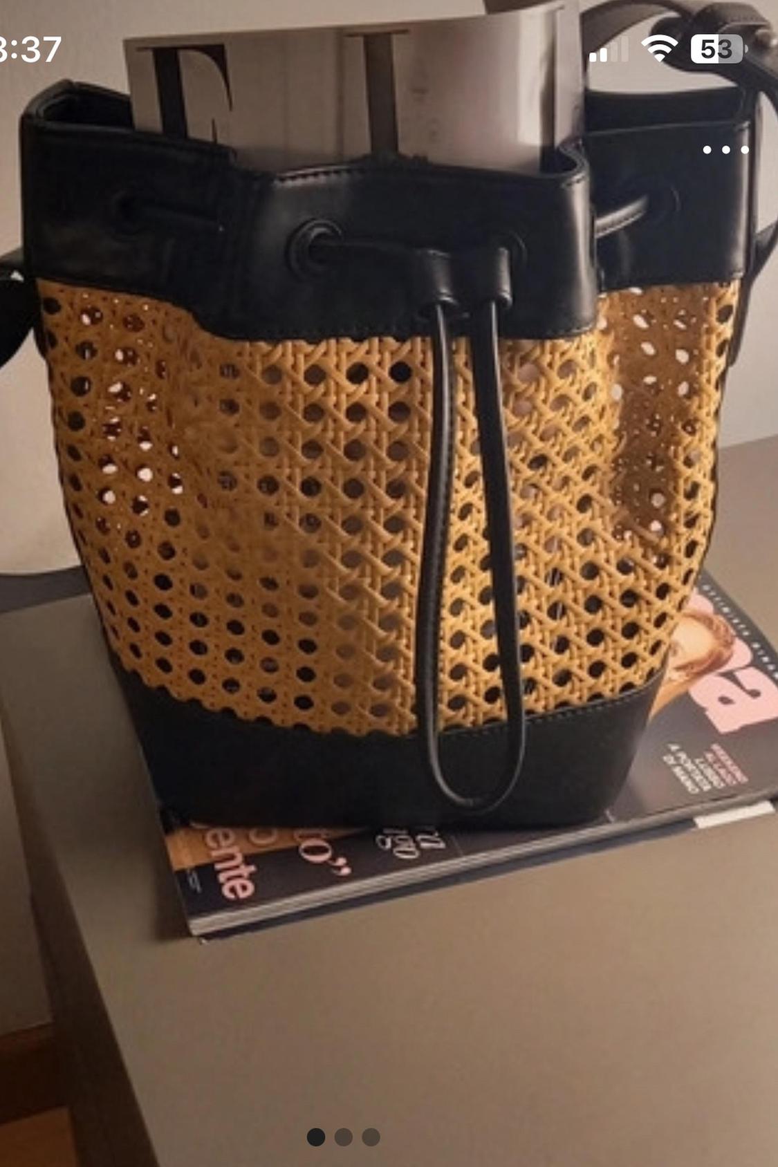 Close-up of a woven bag with a rope handle and black details on a table.