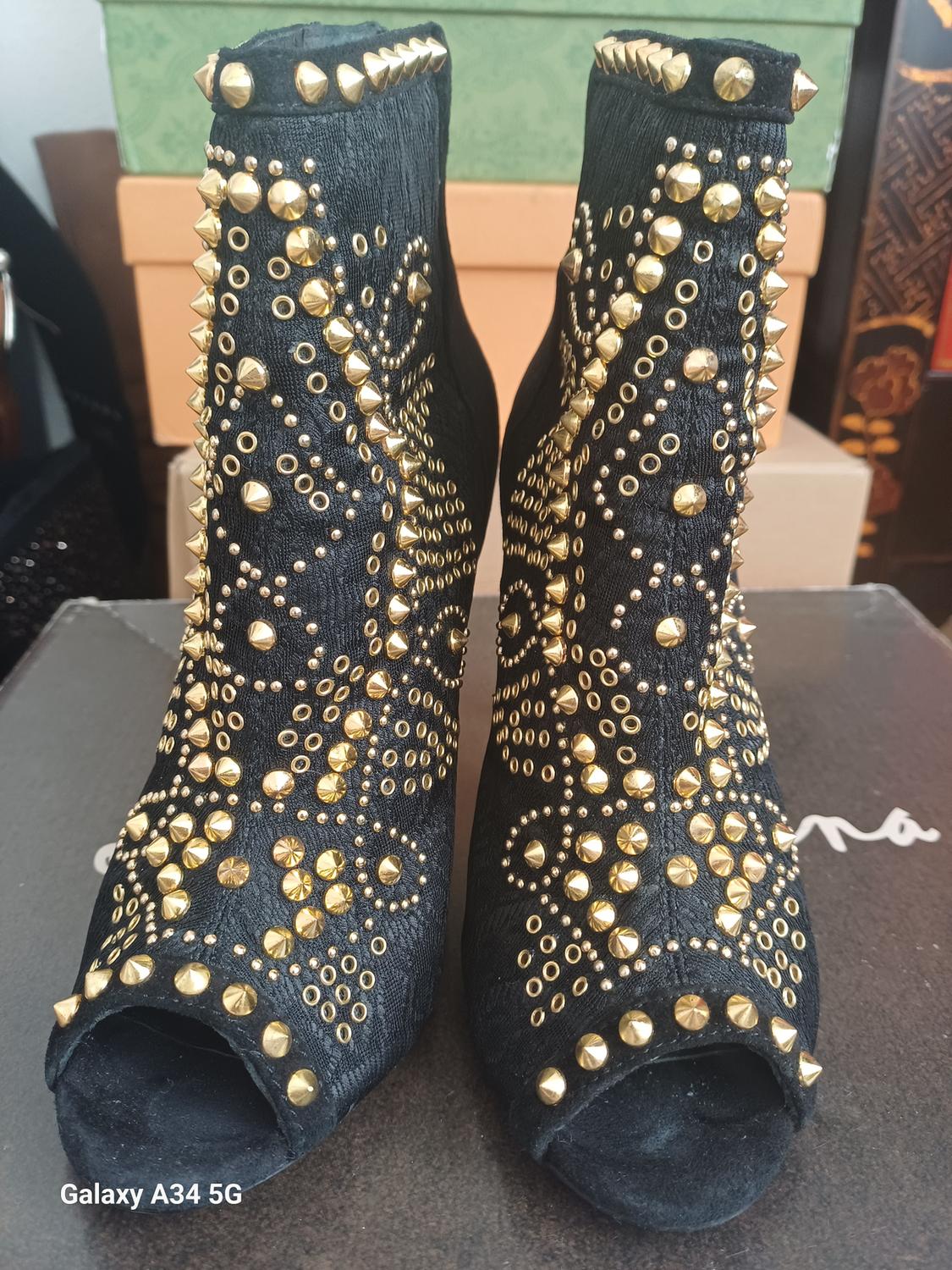 Black ankle boots with gold studs in a geometric design, open toe.