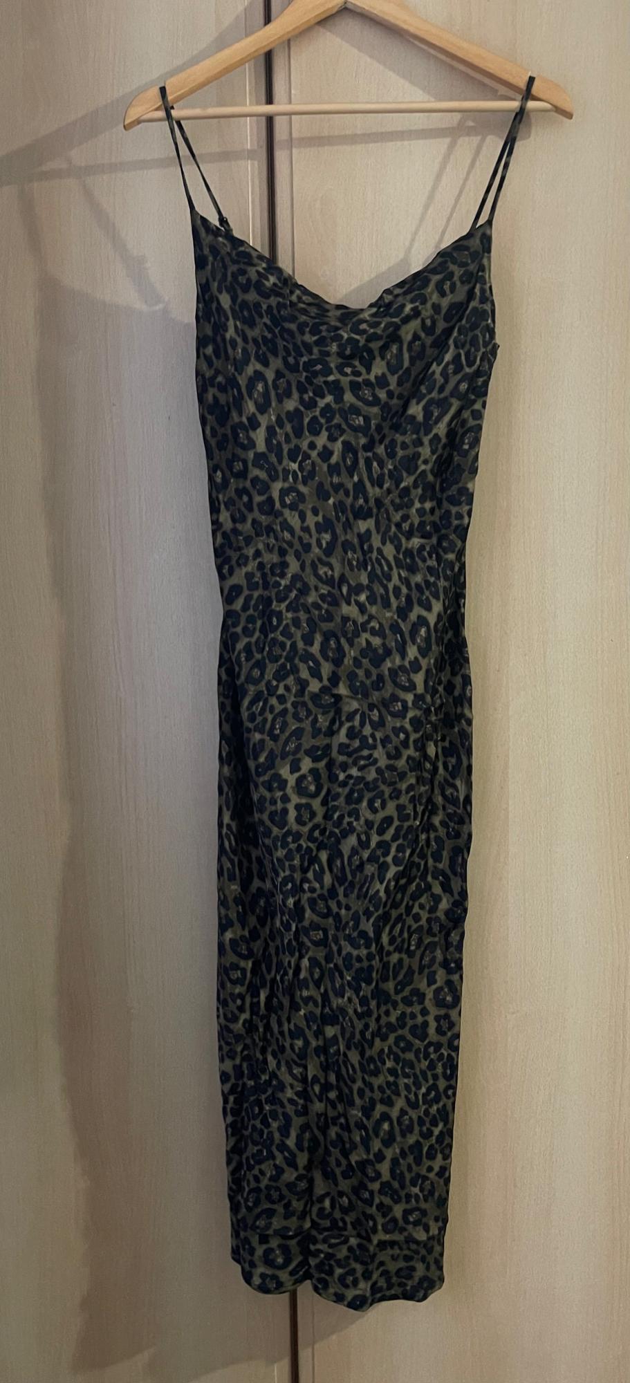 Dark-toned leopard print camisole dress, hanging on a wooden hanger against a light wood background.