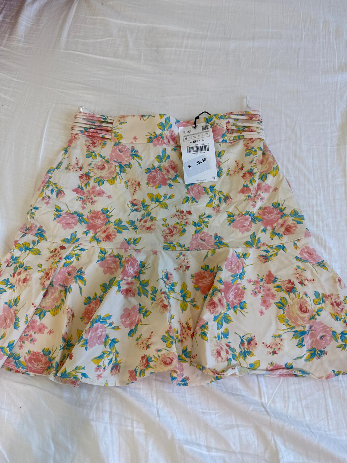 Short skirt with a floral print in pink and yellow tones on a white background. Price tag of $39.90. White fabric background.