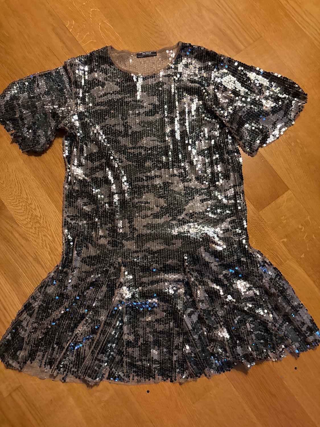 Silver sequin dress with short sleeves and a flared skirt on a light wooden floor.