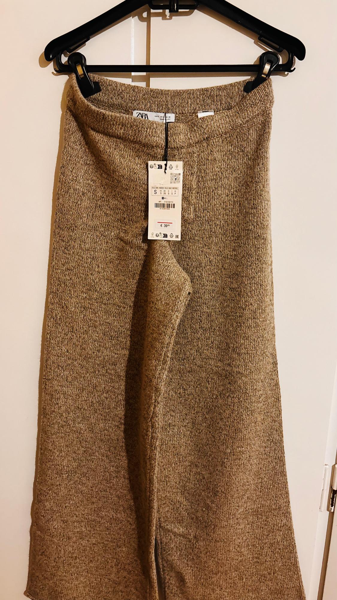 Brown knit trousers hanging on a black hanger, with a visible price tag of €39.95.