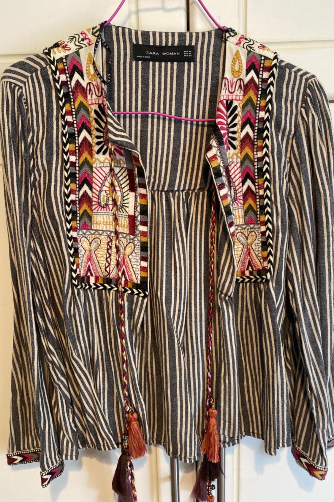 Front view of a striped blouse with colourful embroidery and decorative ties.