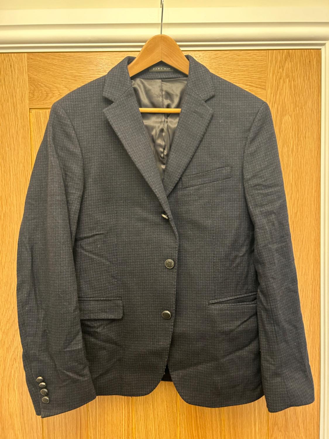 Front view of a dark blue jacket with buttons and front pockets.