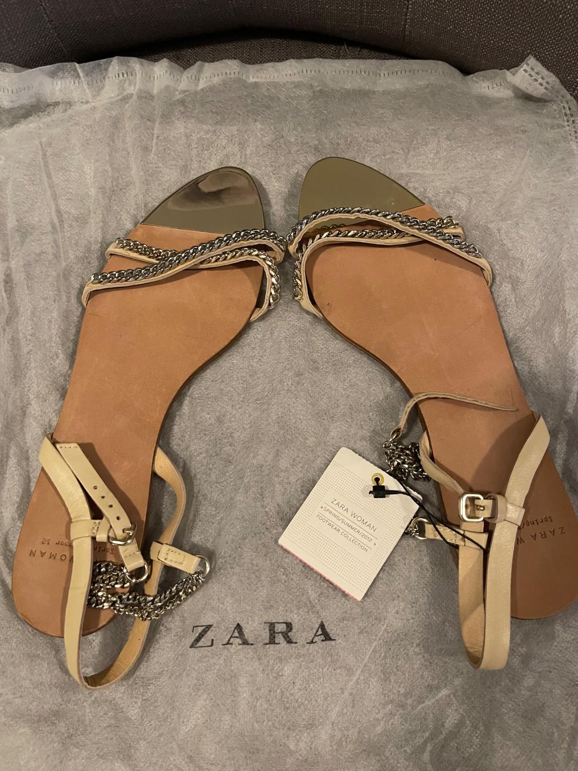 Beige flat sandals with chains on a grey bag. Text: ZARA, ZARA WOMAN, SPRING/SUMMER 2012, FOOTWEAR COLLECTION.