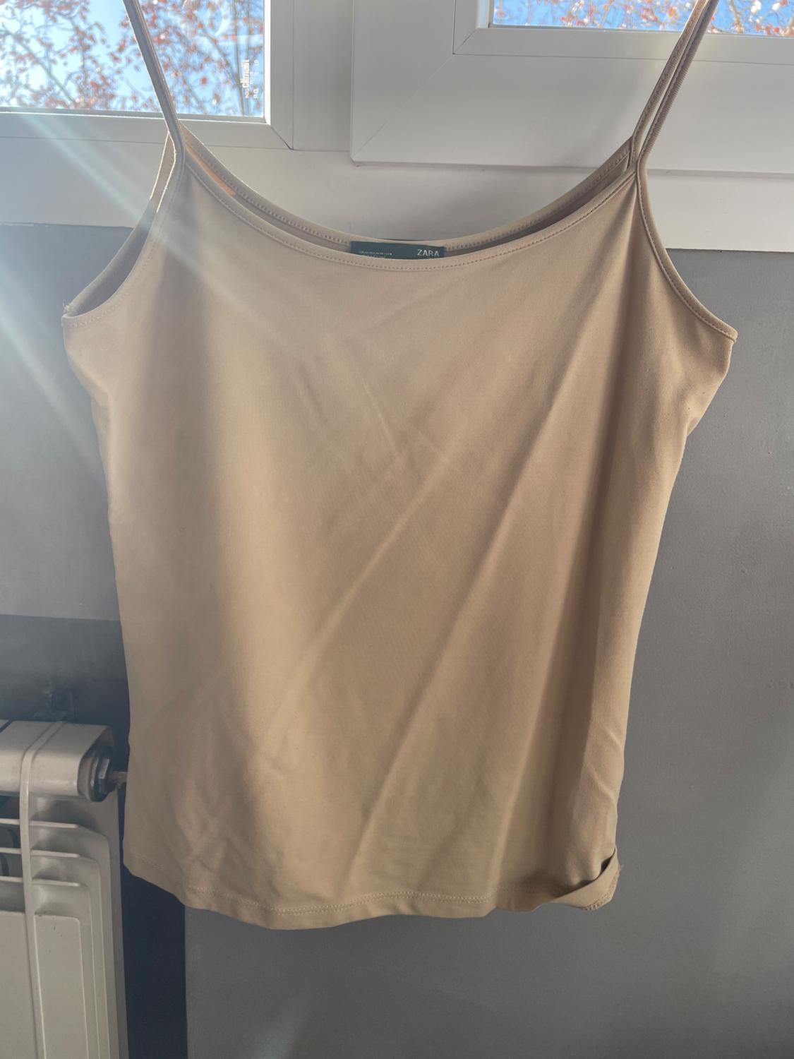 Front view of a hanging beige camisole.