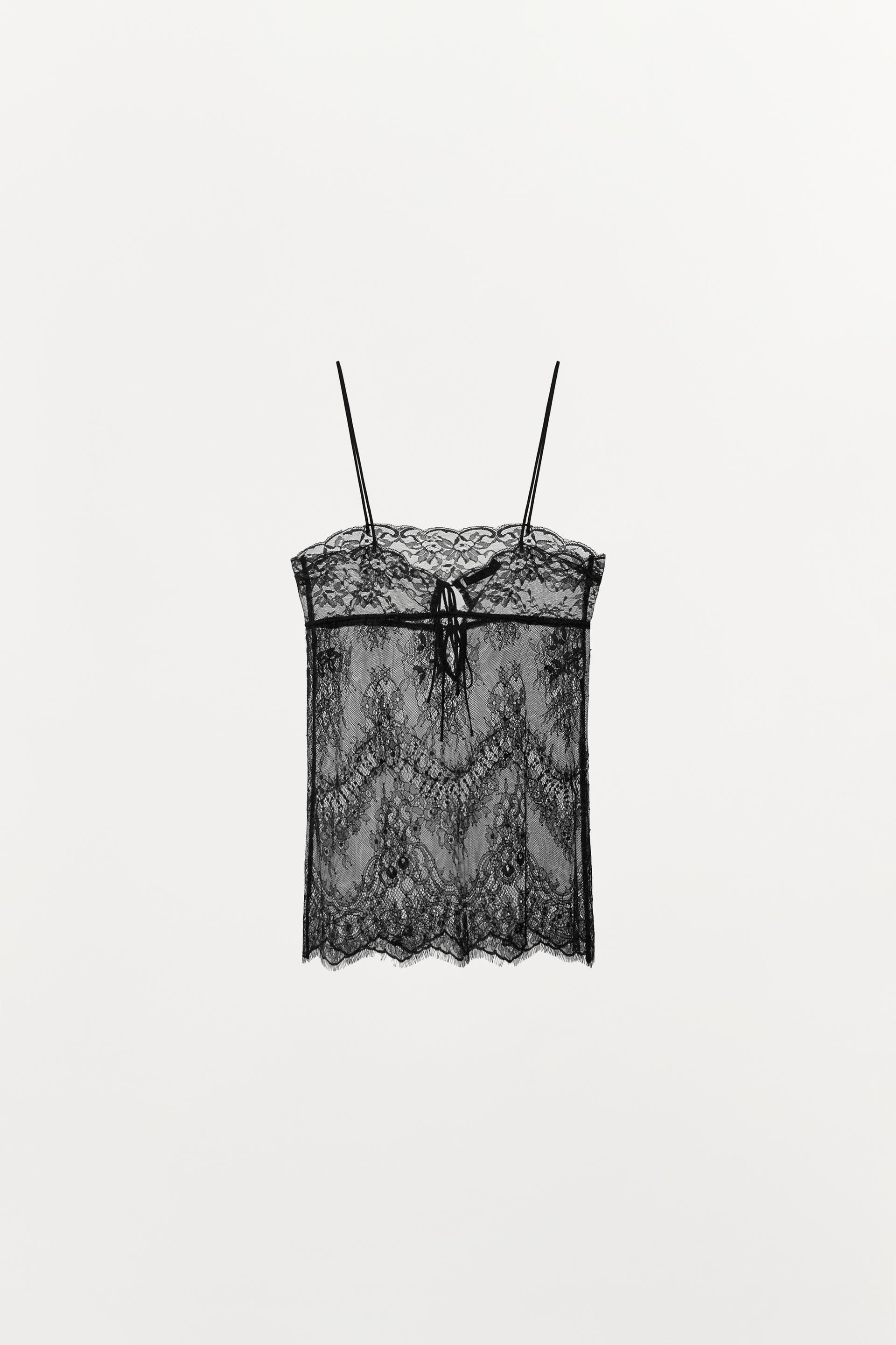 Front view of a semi-sheer black top with lace, thin straps, and a tie at the neckline.