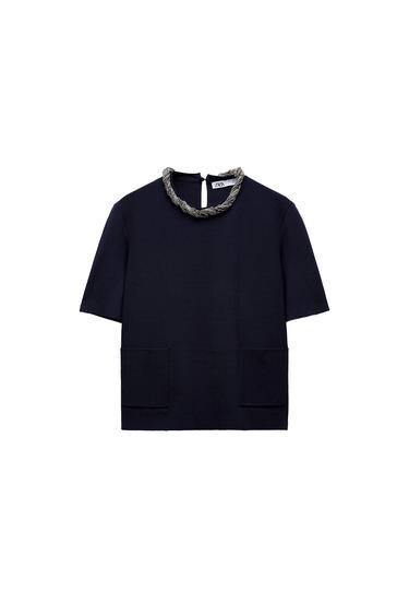 Front view of a black blouse with embellished collar and front pockets