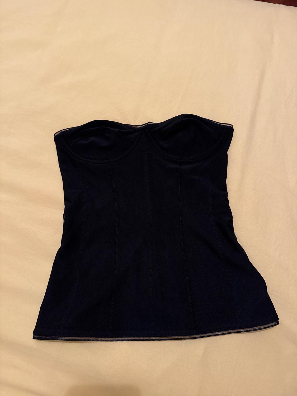 Black strapless corset on a beige surface, with visible seams and a fitted design.