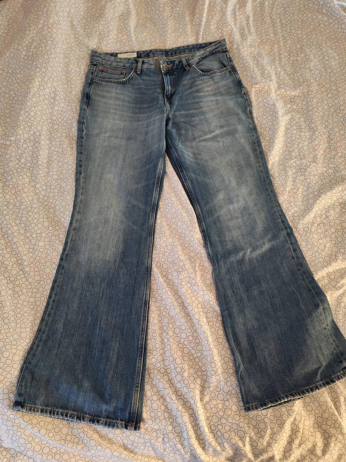 Light blue distressed flared jeans, placed on a quilt with a circle pattern.
