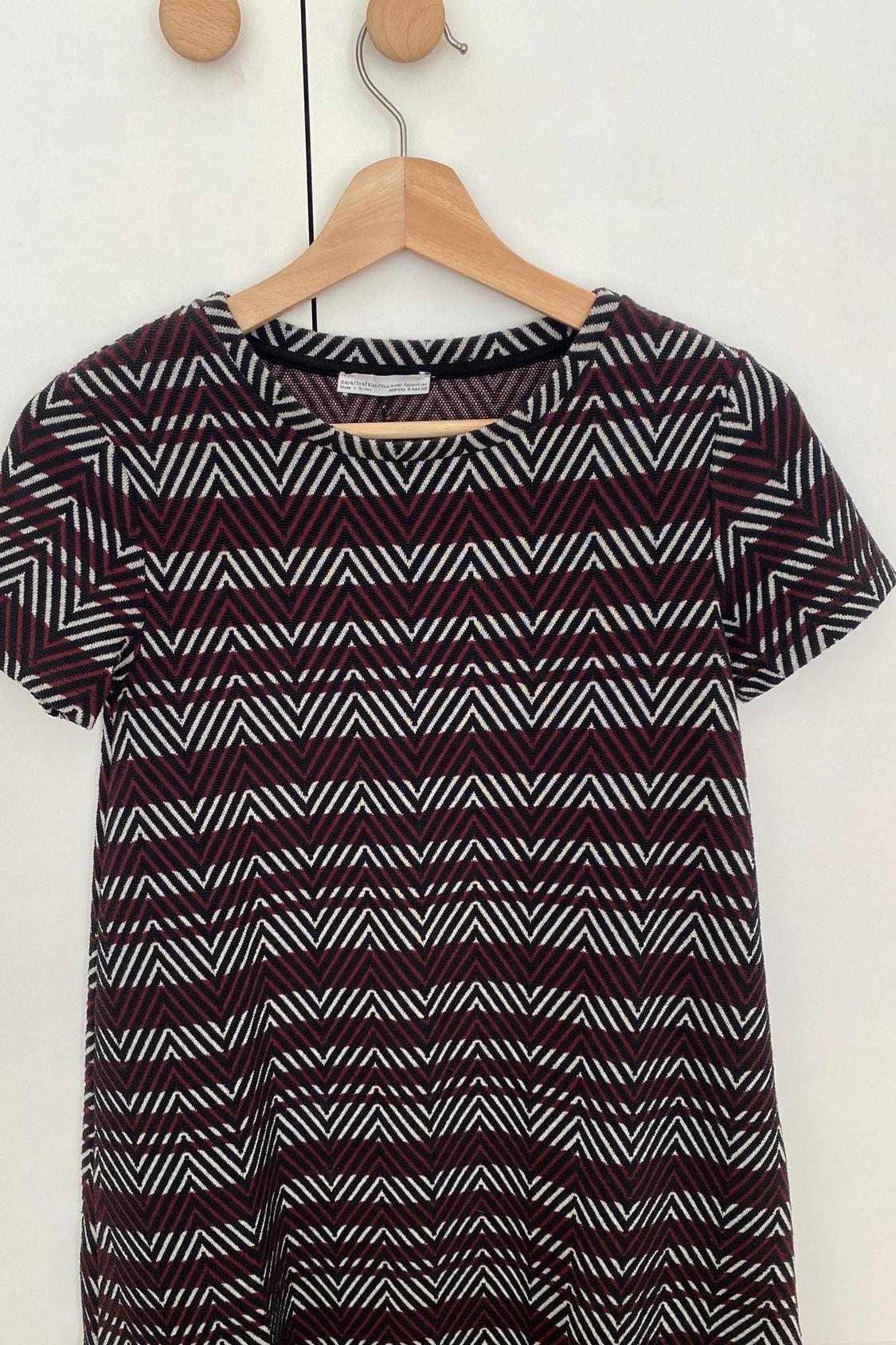 Front view of dress with zigzag print in black, white and red, with short sleeves and round neck.