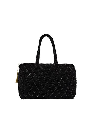 Front view of quilted black handbag with shoulder straps, diamond stitching and zip fastening with pompom.