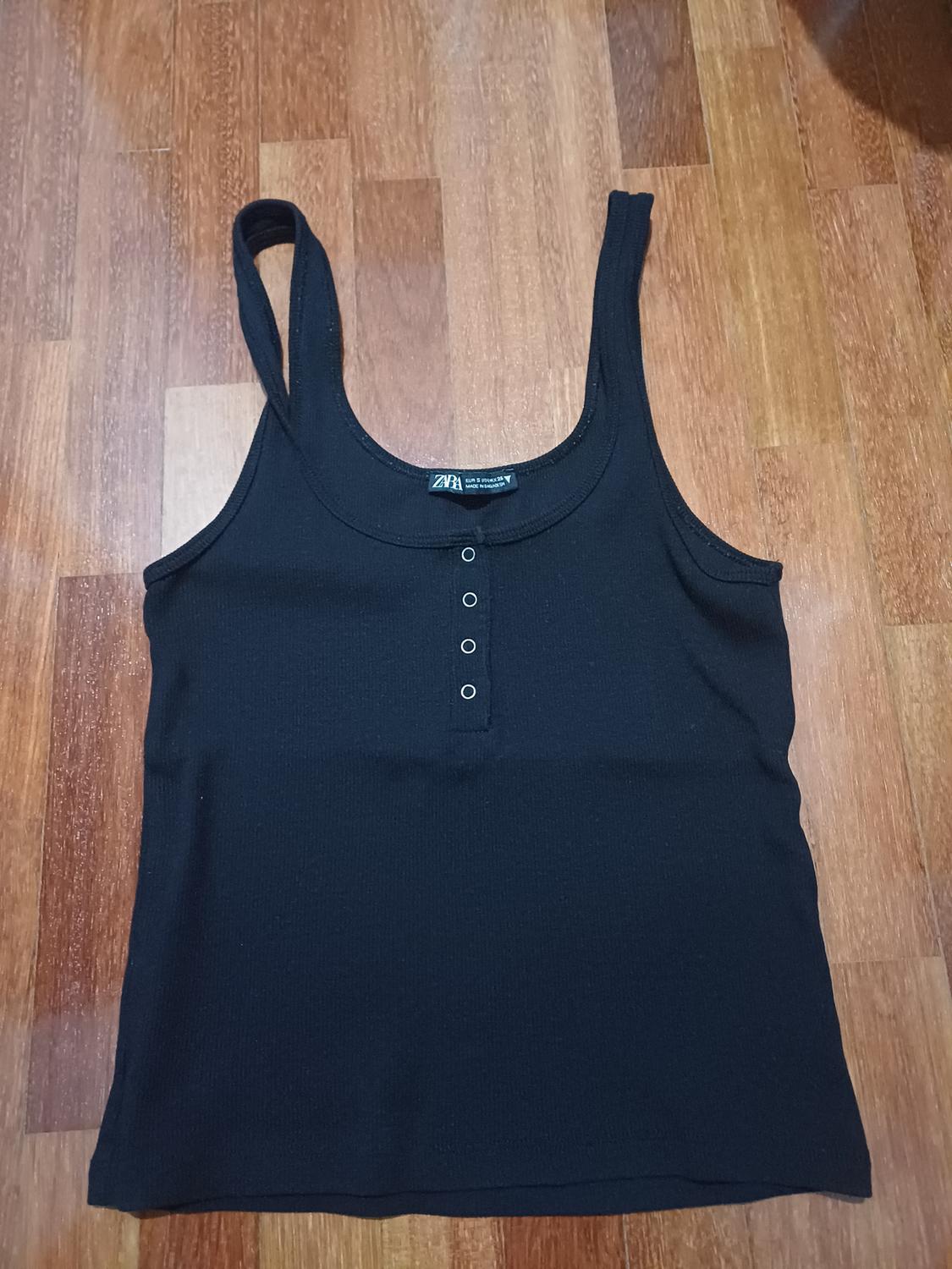 Front view of a black sleeveless t-shirt with a three-button placket.