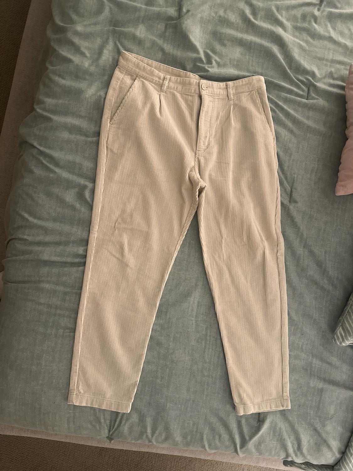 Beige corduroy pants with a texture of vertical stripes, spread out over a grayish-blue comforter.