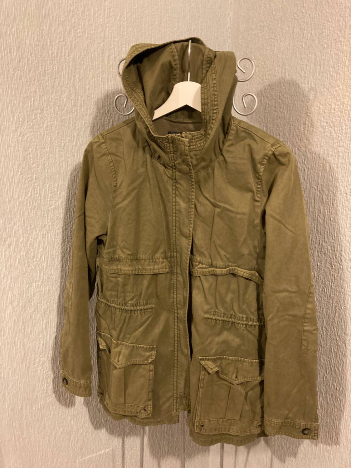 Front view of a green hooded jacket with front flap pockets.