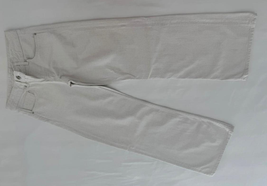 Light-coloured wide-leg trousers laid flat on a white background. Relaxed style composition showing pockets and front fastening.