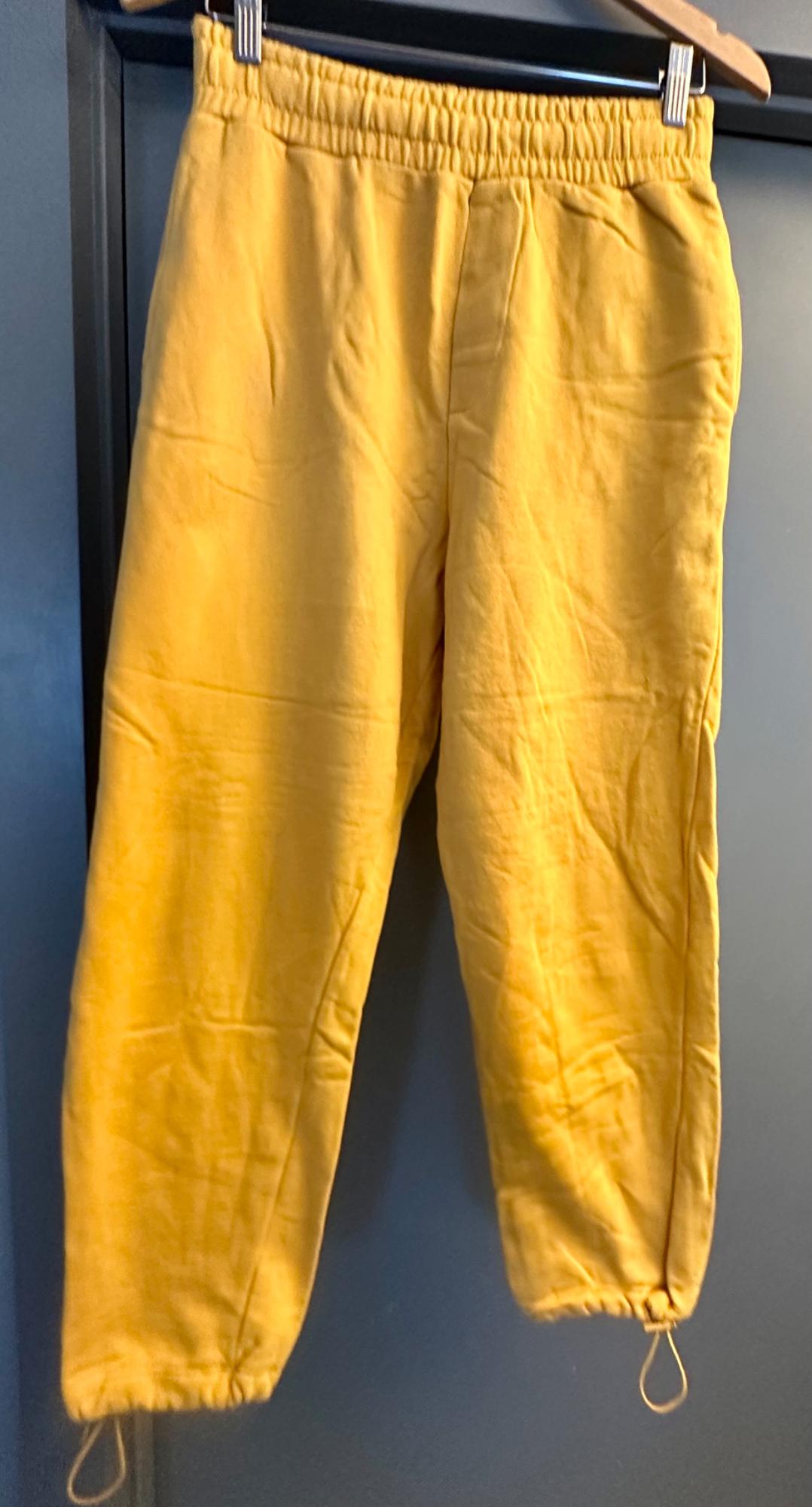 Front view of yellow trousers with elasticated waistband and ankle drawstrings.