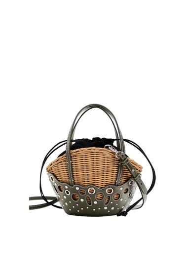 Woven basket bag with dark green perforated leather details, double handles and black drawstring closure.