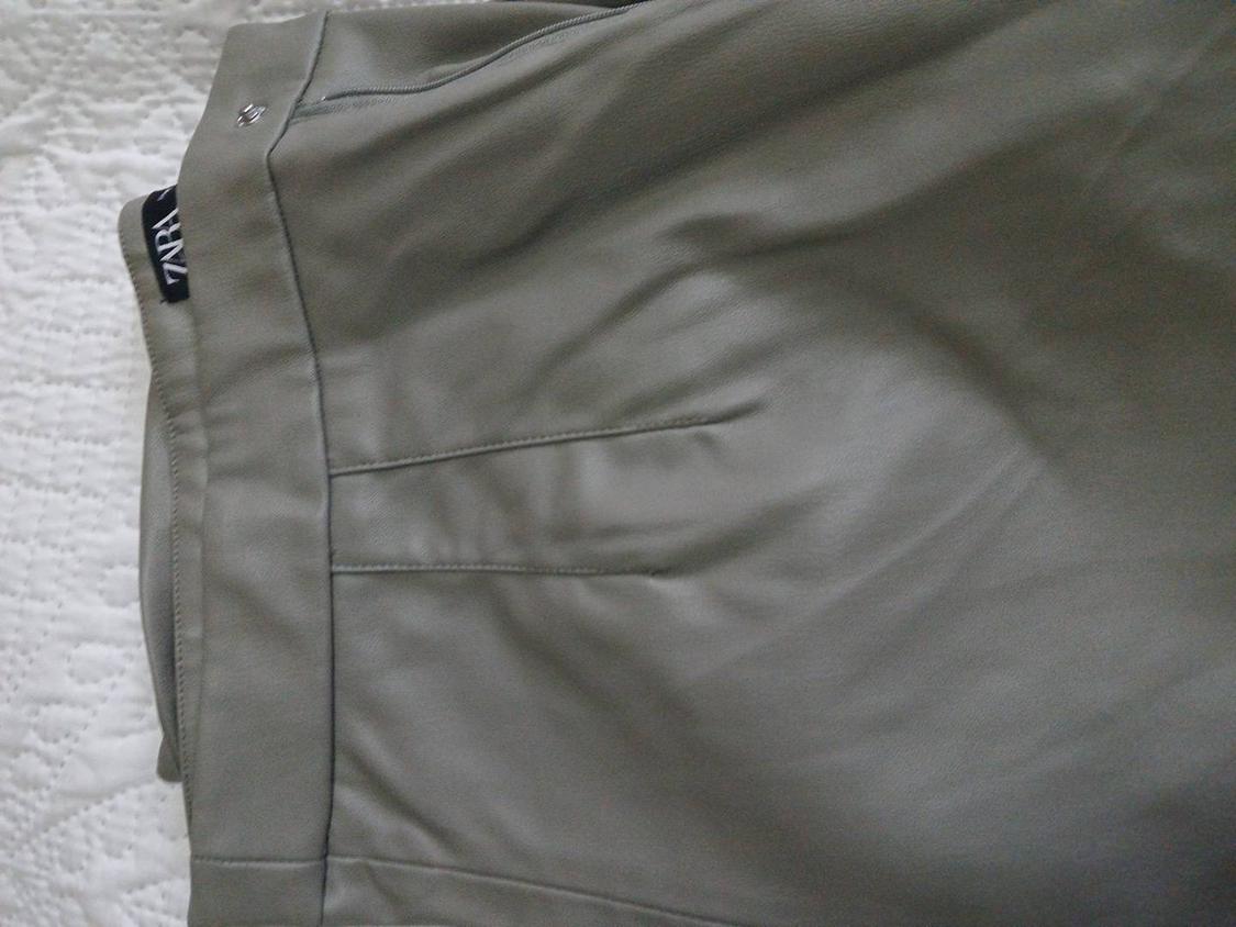 Grey pleated trousers with a side zip on a white surface. Visible label with text "ZARA".