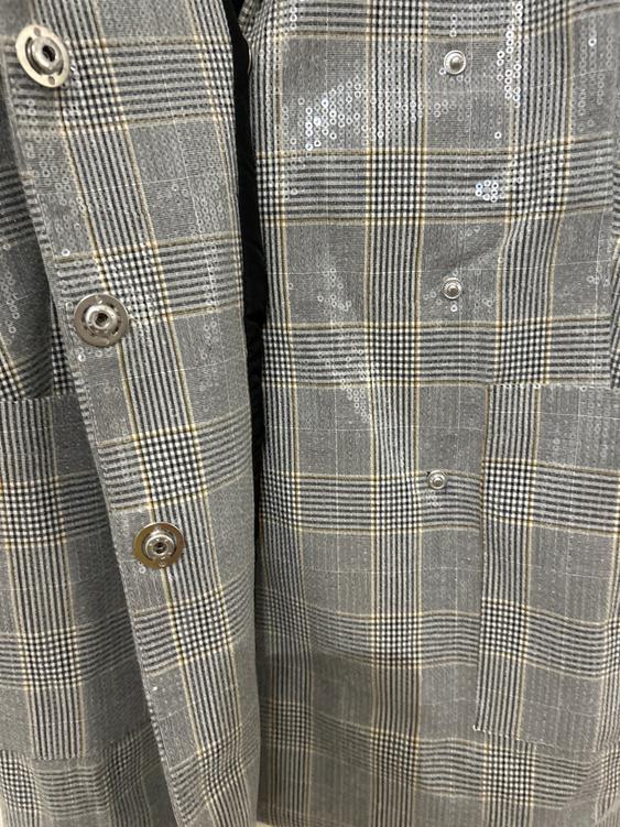 Grey coat fabric with a check print and shimmering sequin details. Metallic buttons visible in the foreground.