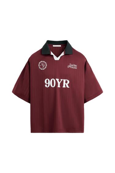 Burgundy t-shirt with black collar, "Feel the Process" and "90YR" text in white. Circular "NJ" logo on the left chest.